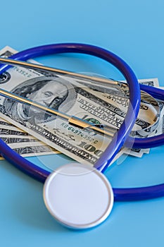 Stethoscope and dollar bills on blue background. Mock-up with copy space for your text. Concept of health care costs and medical