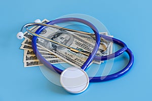 Stethoscope and dollar bills on blue background. Mock-up with copy space for your text. Concept of health care costs and medical