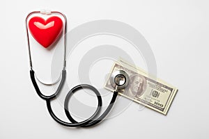 Stethoscope with dollar and red heart on white background, health insurance concept