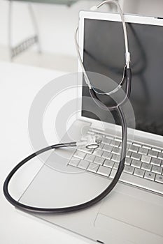 Stethoscope draped over silver laptop