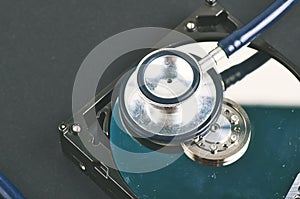 Stethoscope dusty dismantle hard disk over dark background