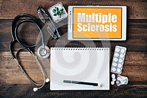 Stethoscope, eyeglass, blank notebook, medicine and digital tablet with MULTIPLE SCLEROSIS word