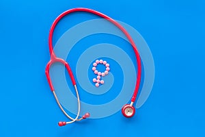 Stethoscope and female symbol for diagnostic and cure of gynaecological disease on blue background top view