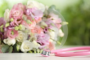 Stethoscope and flowers on  table against blurred background, space for text. World health day