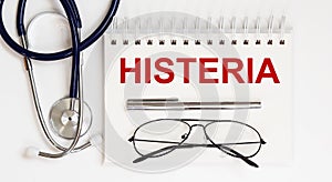 Stethoscope,glasses and pen with notepad with text HISTERIA photo