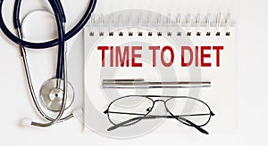 Stethoscope,glasses and pen with notepad with text TIME TO DIET on white background