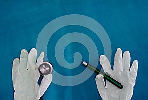 Stethoscope with gloves hold torch on blue surgery background in medical healthcare concept with copy space