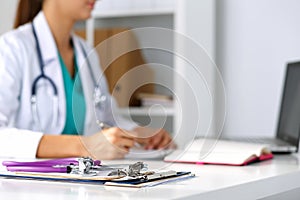 Stethoscope head lying on medical forms on clipboards closeup