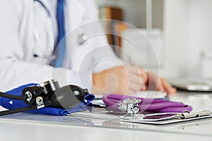 Stethoscope head lying on medical forms on clipboards closeup