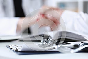 Stethoscope head lying on medical forms closeup