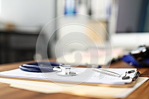 Stethoscope head lying at worktable over patient medical history