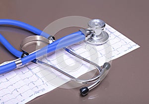 Stethoscope head and silver pen lying on cardiogram clipboard pad. Cardio therapeutist assistance, physician make cardiac physica