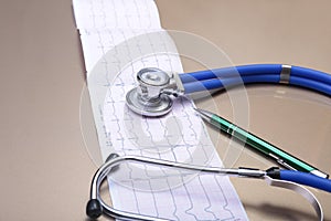 Stethoscope head and silver pen lying on cardiogram clipboard pad. Cardio therapeutist assistance, physician make cardiac physica