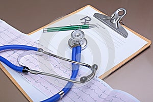 Stethoscope head and silver pen lying on cardiogram clipboard pad. Cardio therapeutist assistance, physician make cardiac physica