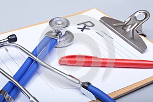 Stethoscope head and silver pen lying on cardiogram clipboard pad. Cardio therapeutist assistance, physician make cardiac physica