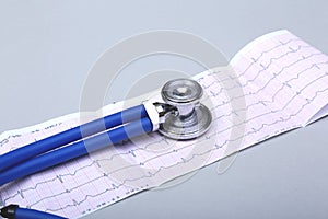 Stethoscope head and silver pen lying on cardiogram clipboard pad. Cardio therapeutist assistance, physician make cardiac physica