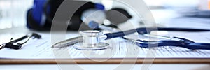 Stethoscope head and silver pen lying on medical application form