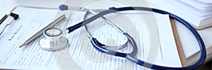 Stethoscope head and silver pen lying on medical application form