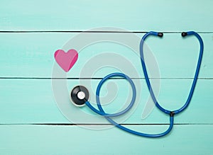 Stethoscope and heart on a blue wooden table. Cardiology equipment for diagnosing cardiovascular diseases. Top view. Flat lay. photo