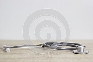 Stethoscope isolated on white wall on a wooden table. Medical tool.