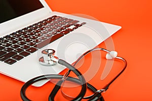 Stethoscope on a laptop on colored background. online medicine concept.