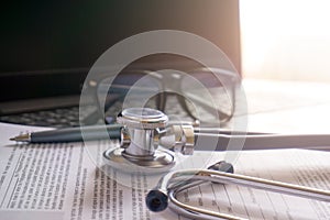 stethoscope lay on computer with pen and glasses, documents.