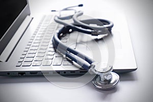 stethoscope lay on computer with pen and glasses, documents. work space