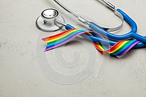 Stethoscope and LGBT rainbow ribbon pride tape symbol. Medical support after sex reassignment surgery. Grey background