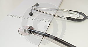 Stethoscope lies on an open empty notebook close-up at the workplace of a family doctor  a medical examination is carried out  the