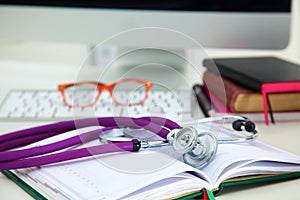 Stethoscope lying on a notebook computer in the background and books