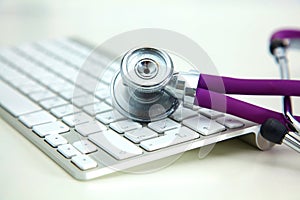 Stethoscope lying on a notebook computer in the background and books