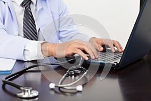 stethoscope is lying on the table near male doctor typing on lap