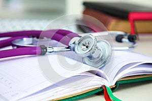 Stethoscope lying on a table on an open book