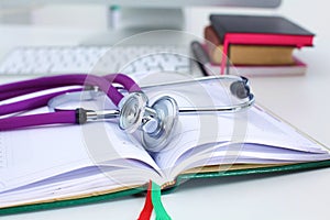 Stethoscope lying on a table an open book