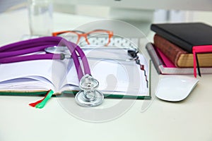 Stethoscope lying on a table an open book