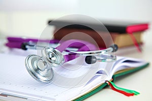 Stethoscope lying on a table an open book