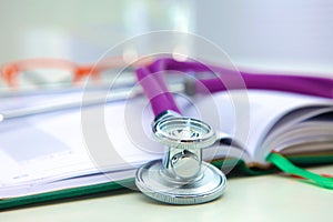Stethoscope lying on a table an open book