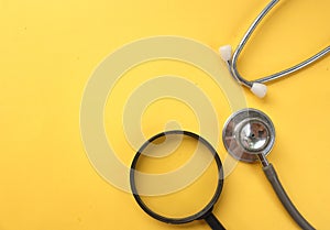 Stethoscope and Magnifying glass on a yellow background