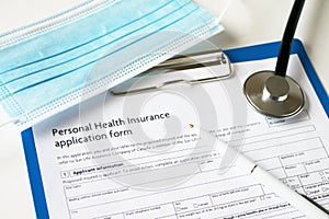 Stethoscope  mask  white pen on clipboard with health insurance form