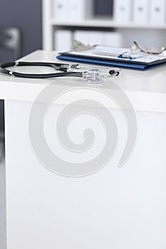 Stethoscope and medical history form lying at reception desk. Medical tools at doctor working table in clinic or