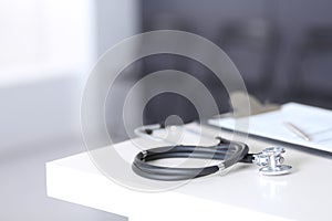 Stethoscope and medical history form lying at reception desk. Medical tools at doctor working table in clinic or