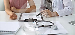 Stethoscope, medical prescription form are lying against the background of a doctor and patient discussing health exam