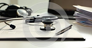 Stethoscope with medical tablet with documents on table in clinic