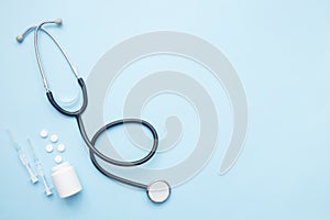Stethoscope, medication pills and syringe on blue flat lay background. Diagnostics concept. Top view, flat lay, copy space