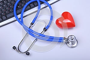 Stethoscope on modern laptop computer. red heart on white table with space for text. Healthcare concept