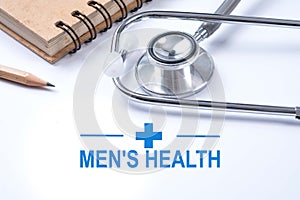Stethoscope, notebook and pencil with men`s health words. Health