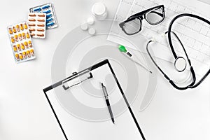 Stethoscope in the office of doctors.Top view of doctor`s desk table, blank paper on clipboard with pen. Copy space