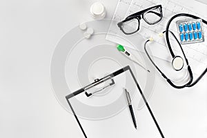 Stethoscope in the office of doctors.Top view of doctor`s desk table, blank paper on clipboard with pen. Copy space