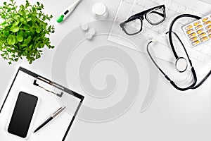 Stethoscope in the office of doctors.Top view of doctor`s desk table, blank paper on clipboard with pen. Copy space