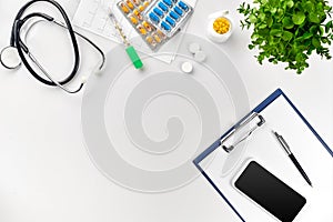Stethoscope in the office of doctors.Top view of doctor`s desk table, blank paper on clipboard with pen. Copy space